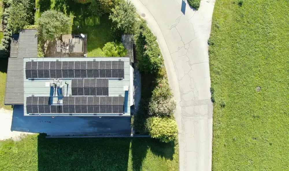 Drohnenshot von einem Haus mit PV-Anlage am Dach im Grünen
