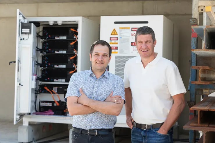 2 Männer vor großem Batteriespeicher
