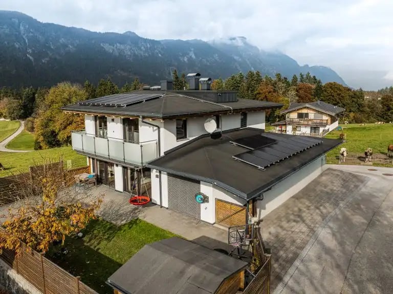 Einfamilienhaus mit PV Anlage am Dach mit Bergkette im Hintergrund in Kufstein