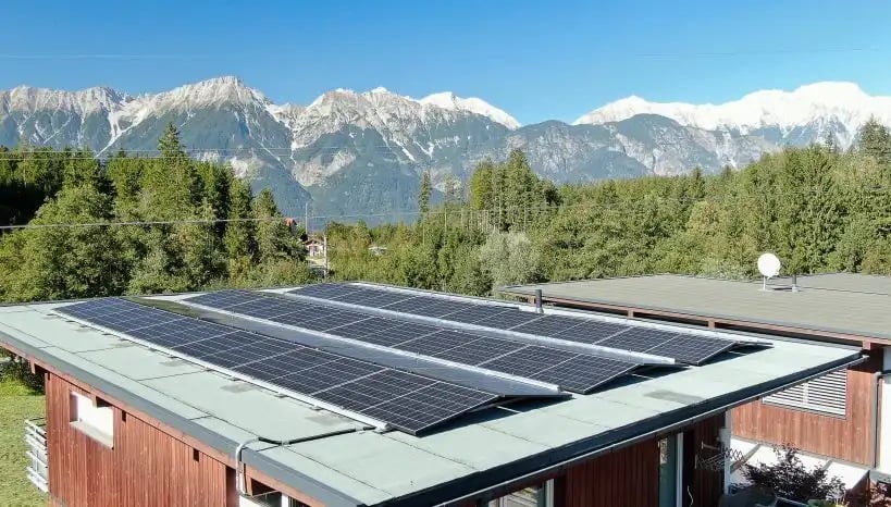 Dach eines Hauses mit PV Anlage und Bergkette im Hintergrund