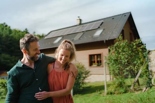Paar vor Eigenheim mit PV-Anlage