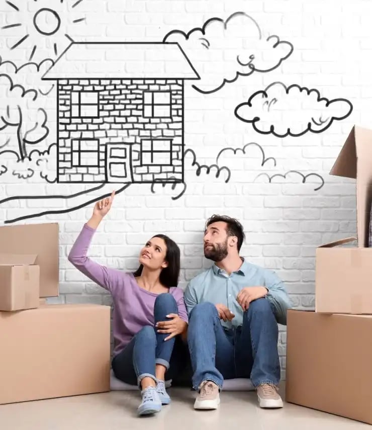 Frau und Mann am Boden sitzend mit Hausillustration im Hintergrund und Umzugskartons