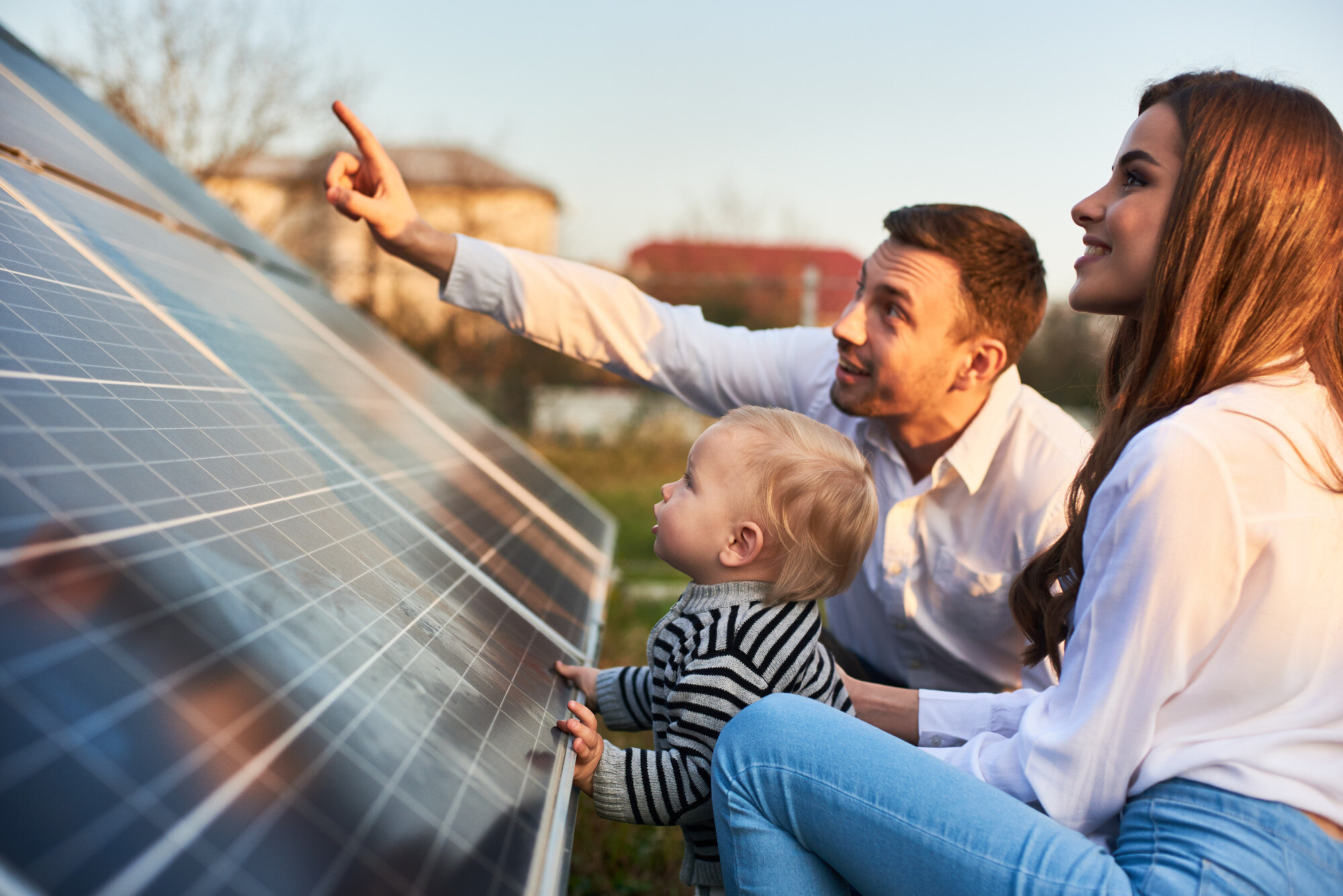 Eltern mit Kind vor PV-Anlage - Klein